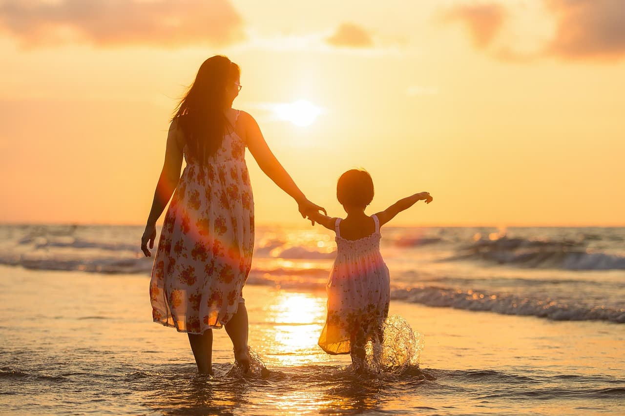 Mulher na praia com filho ao fim da tarde